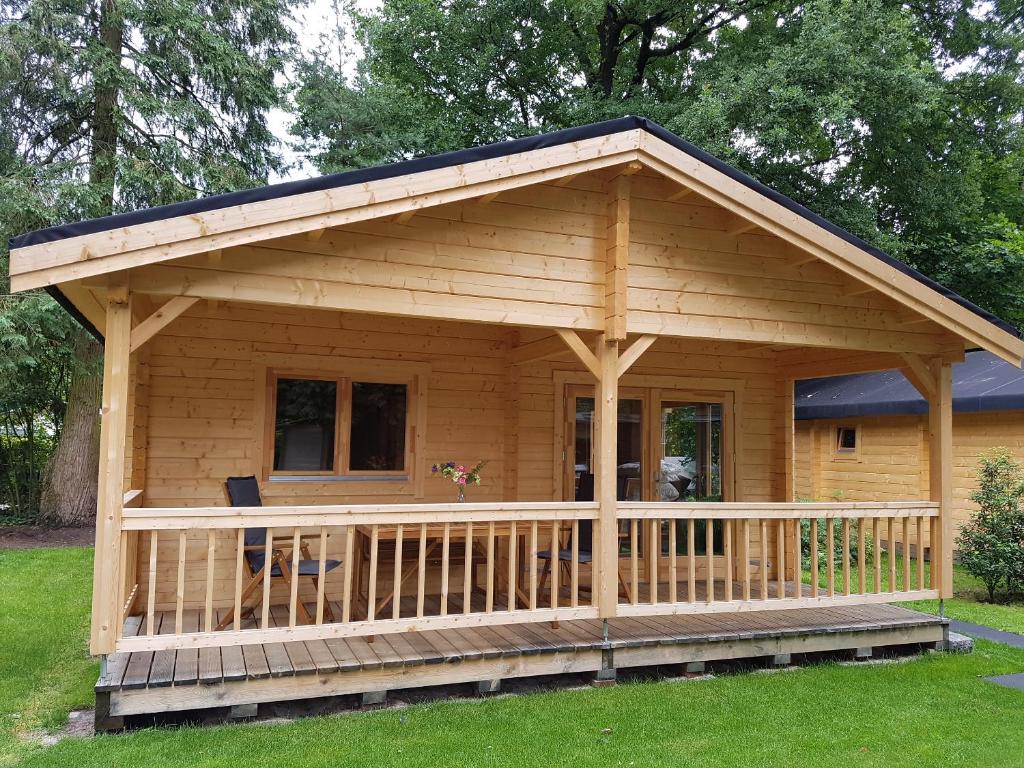 een grote houten hut met een veranda bij HderH - Eco Lodge op vakantiepark De IJsvogel, zwembaden, kids fun, natuur en rust in Voorthuizen