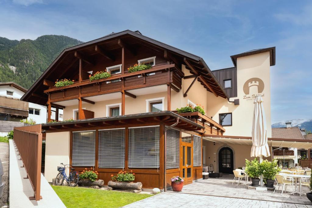 een huis met een balkon en een patio bij Aparthotel Zum Schlössl in Villa Ottone