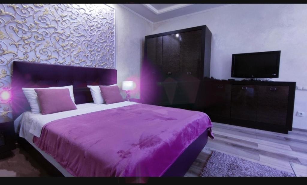 um quarto roxo com uma cama e uma televisão em Best Apartment Plosha Rynok em Lviv