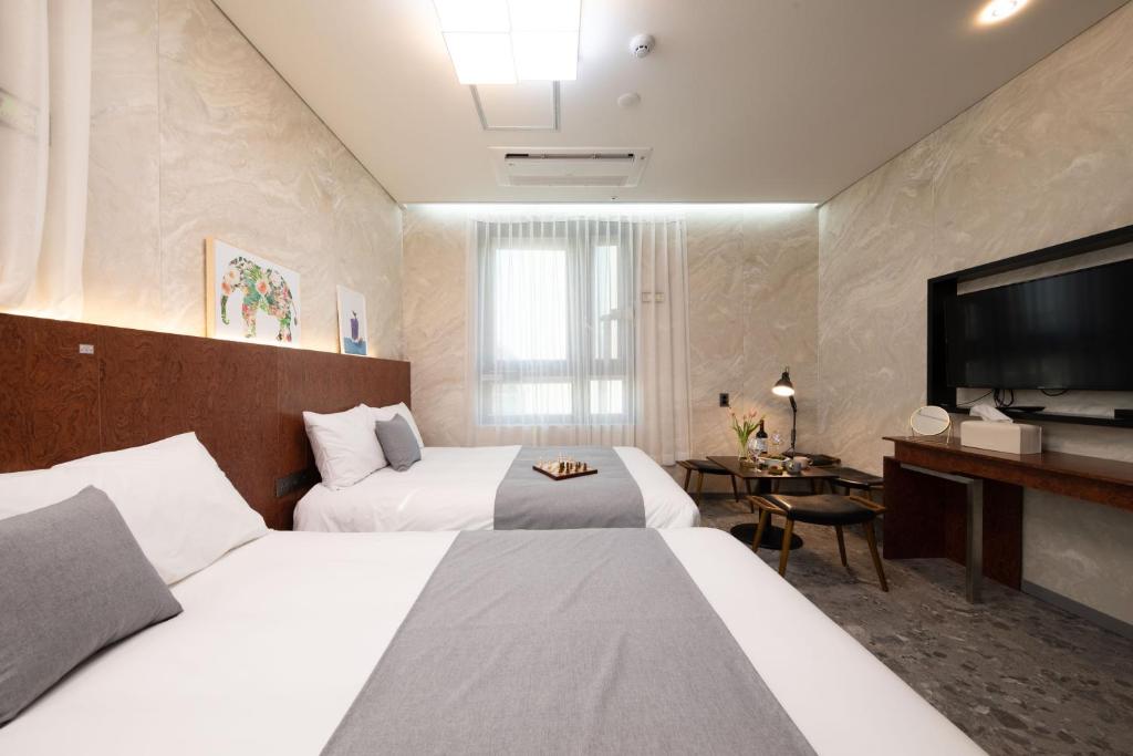 首爾的住宿－Hotel DM，酒店客房设有两张床和一台平面电视。