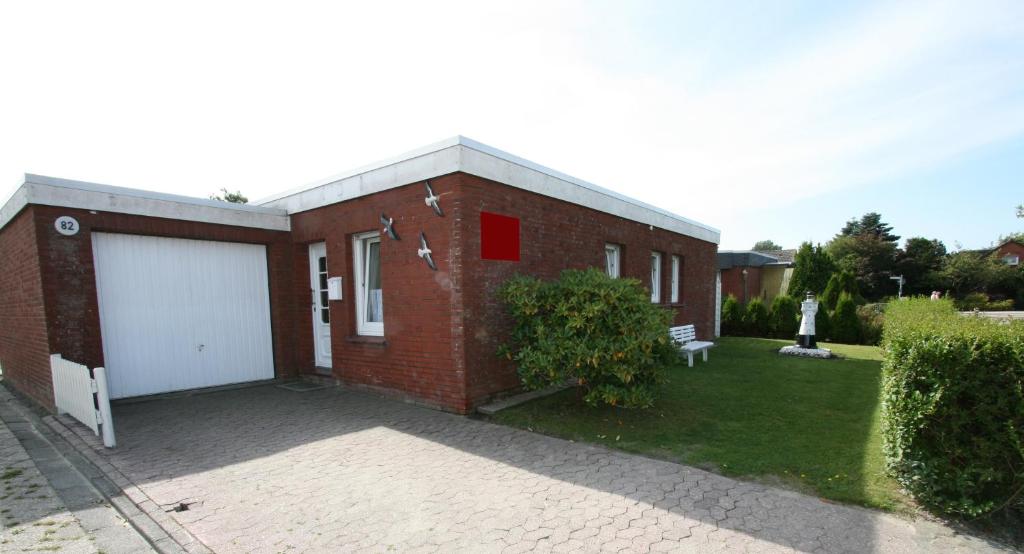 a red brick building with a white garage at Ferienhaus Pelikanstr 82 Ostermann Bungalow 3 in Norddeich