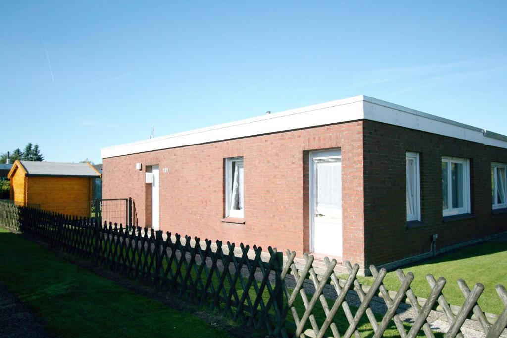 Ferienhaus Pelikanstr 129 Ostermann Bungalow 5 في نورديش: منزل من الطوب وامامه سياج