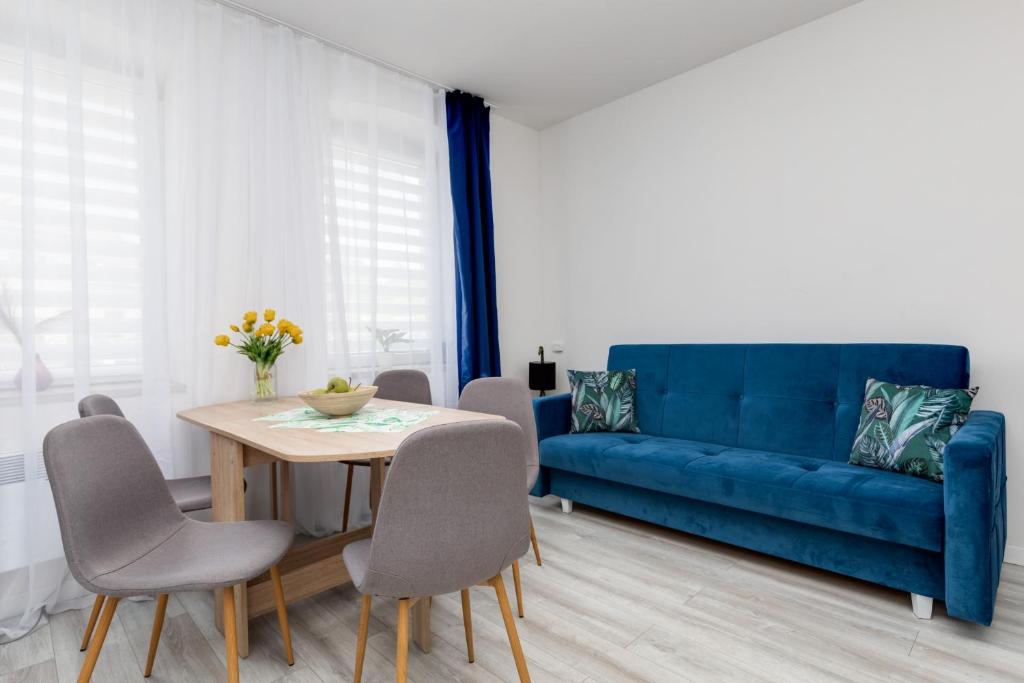 a living room with a blue couch and a table at Apartament nad Jeziorem Kołczewo - Ogród & Parking by Renters in Kołczewo