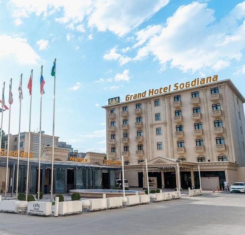 GRAND HOTEL SOGDIANA في سمرقند: مبنى الفندق مع وجود اعلام امامه