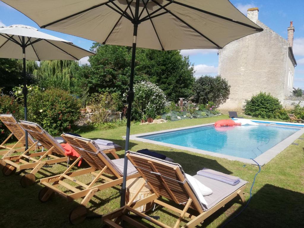 um grupo de cadeiras e um guarda-sol junto a uma piscina em Le Clos de l'Aiguillon 