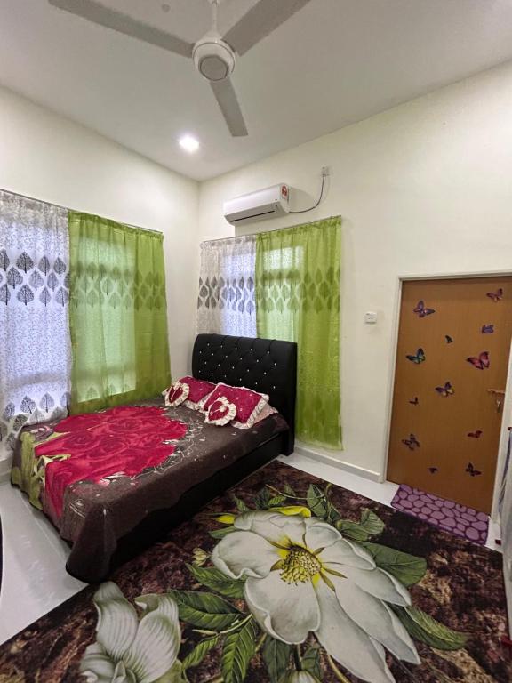 una camera da letto con un letto fiorito sul pavimento di Teratak Cikgu Din a Marang
