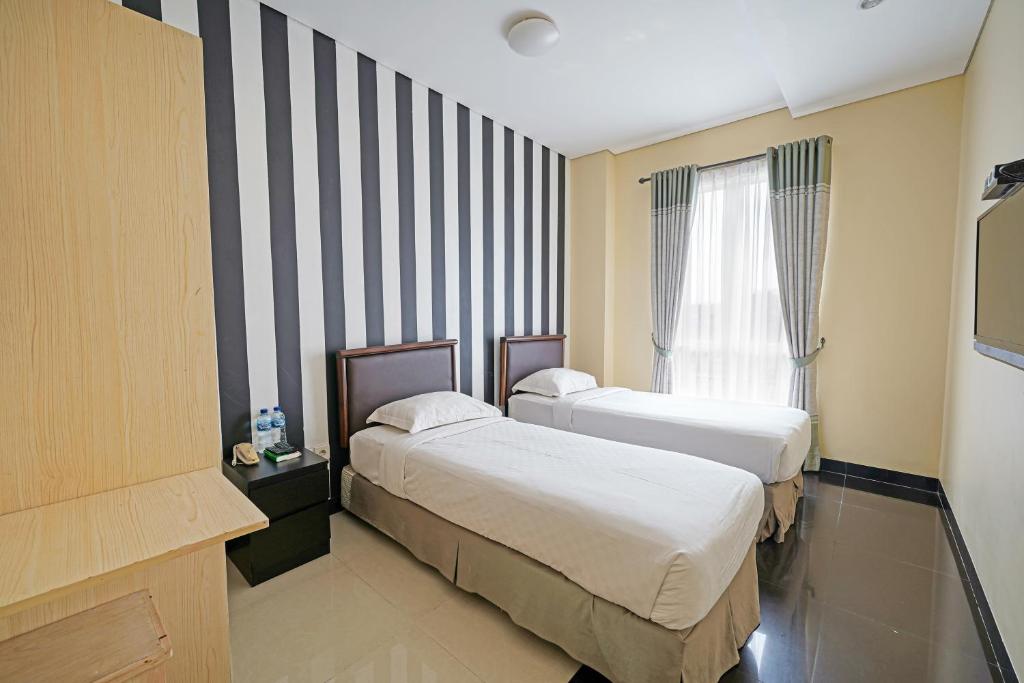 a hotel room with two beds and a window at Multi 88 Syariah in Jakarta