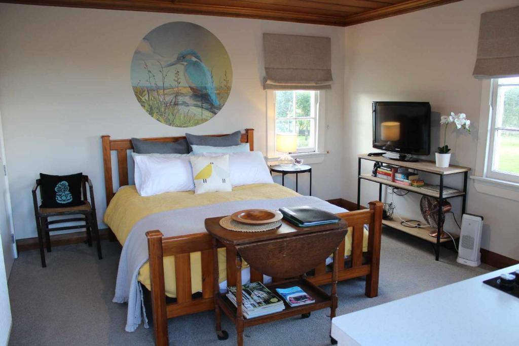 - une chambre avec un lit, une table et une télévision dans l'établissement The Studio - Huntly House, à Auckland