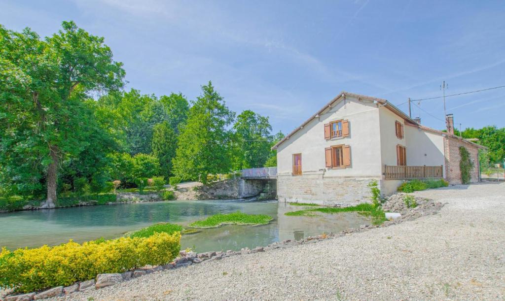 uma casa ao lado de um rio com um edifício em Le moulin de la lhuitrelle 