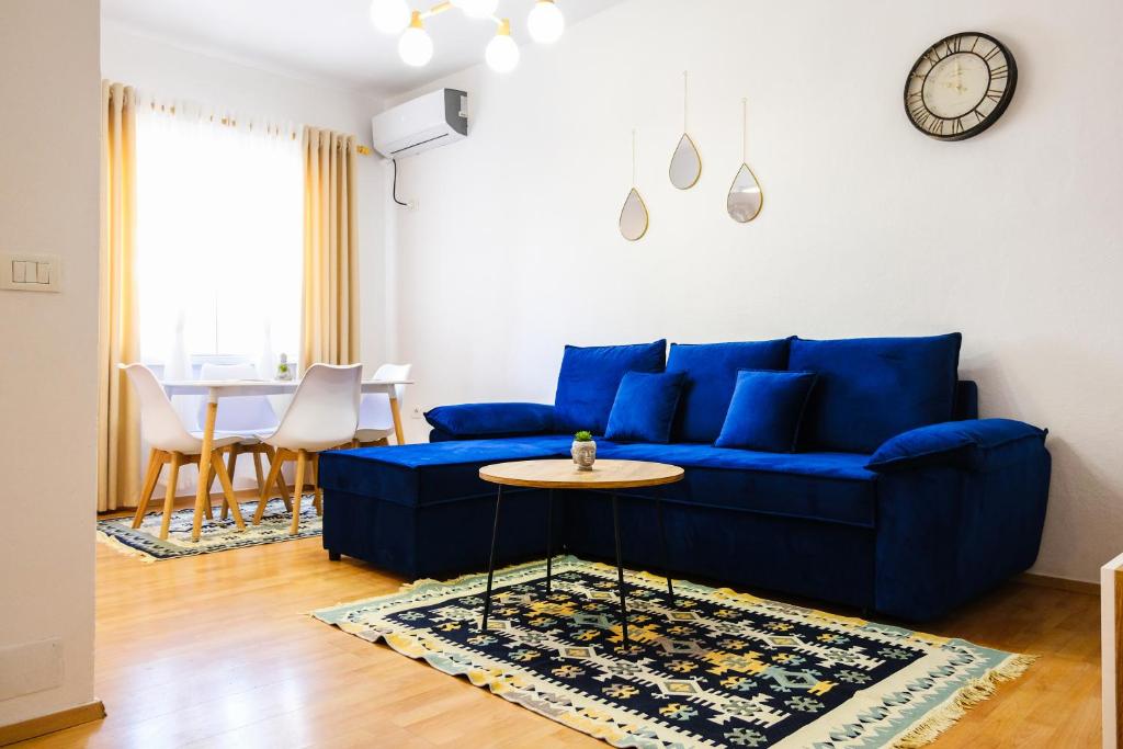ein blaues Sofa im Wohnzimmer mit einem Tisch in der Unterkunft Matias sweetest home in Tirana