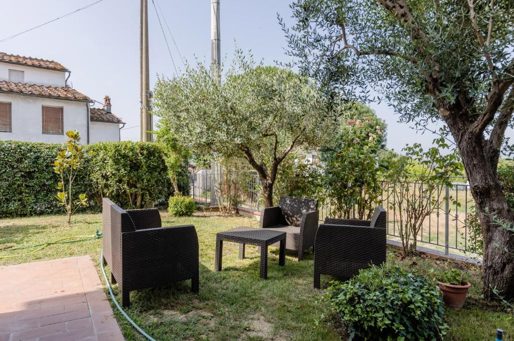 a yard with chairs and a table and trees at Casa Vacanza Rocchetti with Parking&Garden! in Porcari