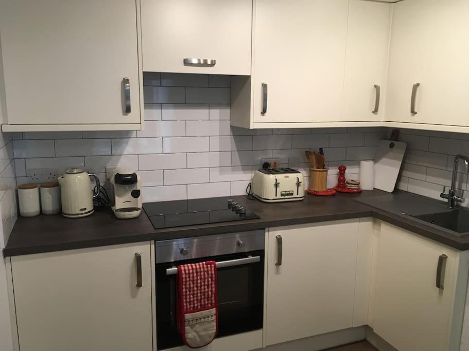 La cuisine est équipée de placards blancs et d'un four avec plaques de cuisson. dans l'établissement Caledonian - Charming Central 1 Bed Flat, à Édimbourg