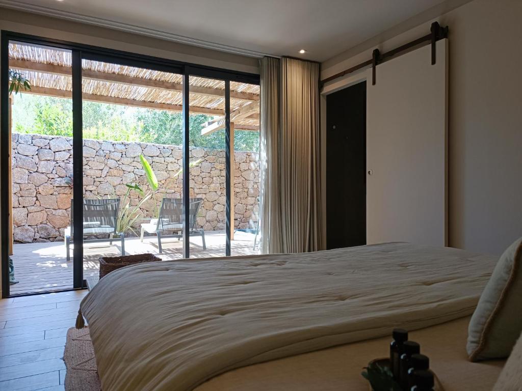 een slaapkamer met een groot bed en een groot raam bij Hôtel Les Suites Du Maquis in Bonifacio