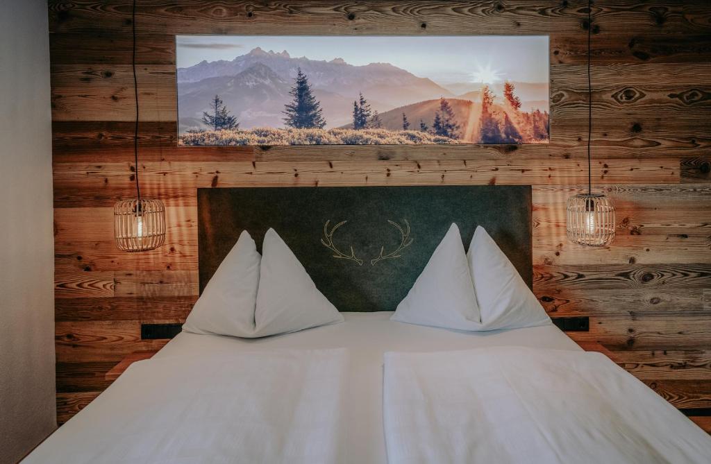 ein Bett mit weißen Kissen und einem Bild an der Wand in der Unterkunft Frühstückspension Friedheim in Filzmoos