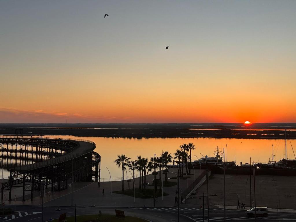 un tramonto su un corpo di acqua con palme di Ría de Huelva a Huelva