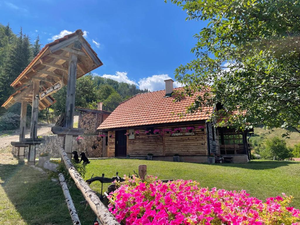 a log cabin with pink flowers in front of it at Konak Mandica avlija in Zaovine