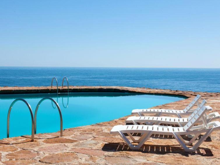 - un ensemble de chaises longues installées à côté de la piscine dans l'établissement APARTAMENTO CAP SA SAL CON VISTAs PRIVILEGIADAS, à Gérone