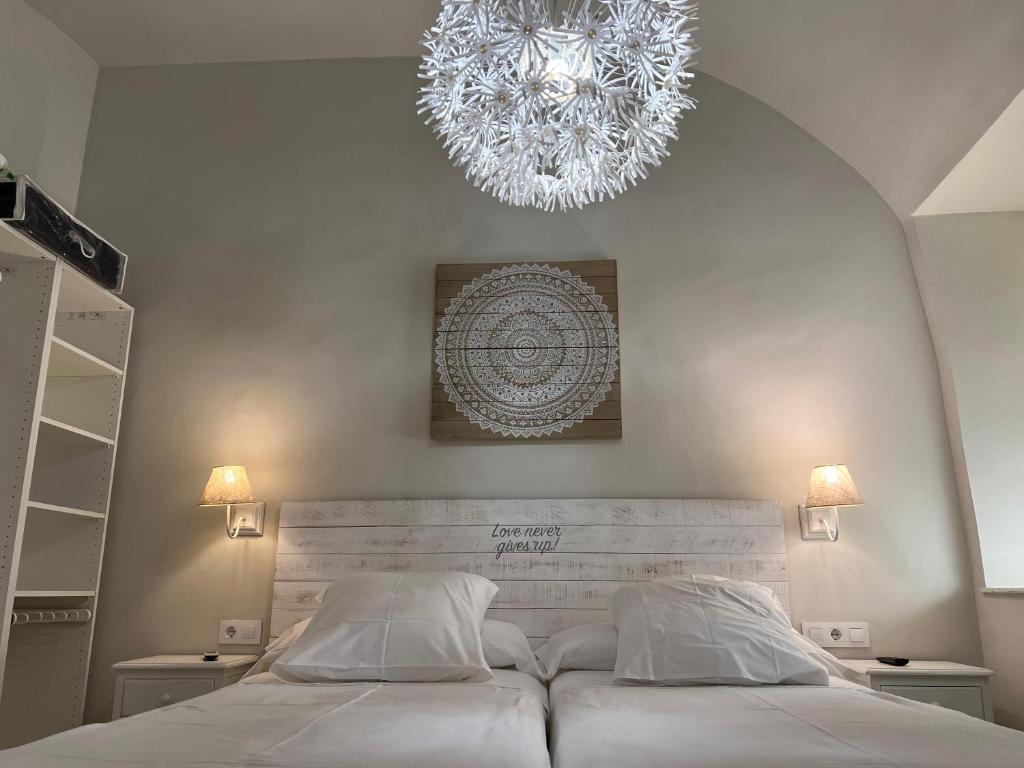 a bedroom with a large white bed with a chandelier at Aljara Mezquita in Córdoba