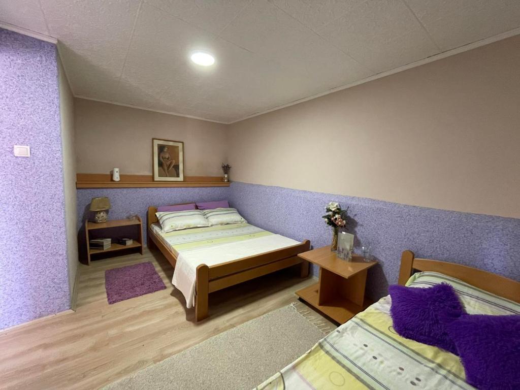 um quarto com 2 camas e paredes roxas em Petlov Konak em Mala Remeta