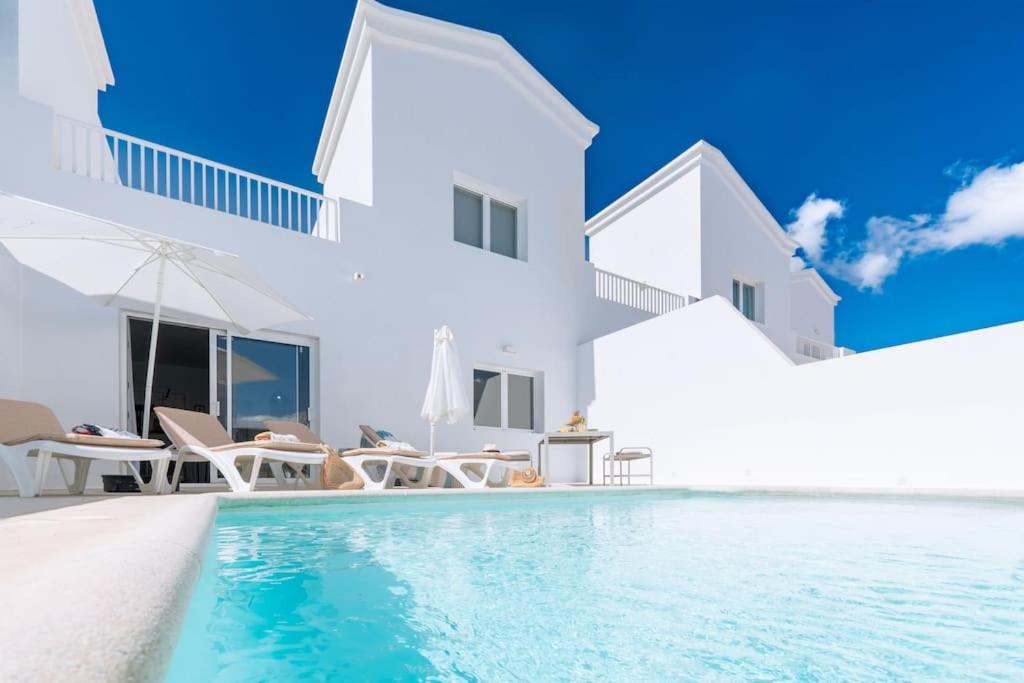 een wit huis met een zwembad ervoor bij Casa Lolalo - Modern Villa with pool, 15min walk to Marina Rubicón in Playa Blanca