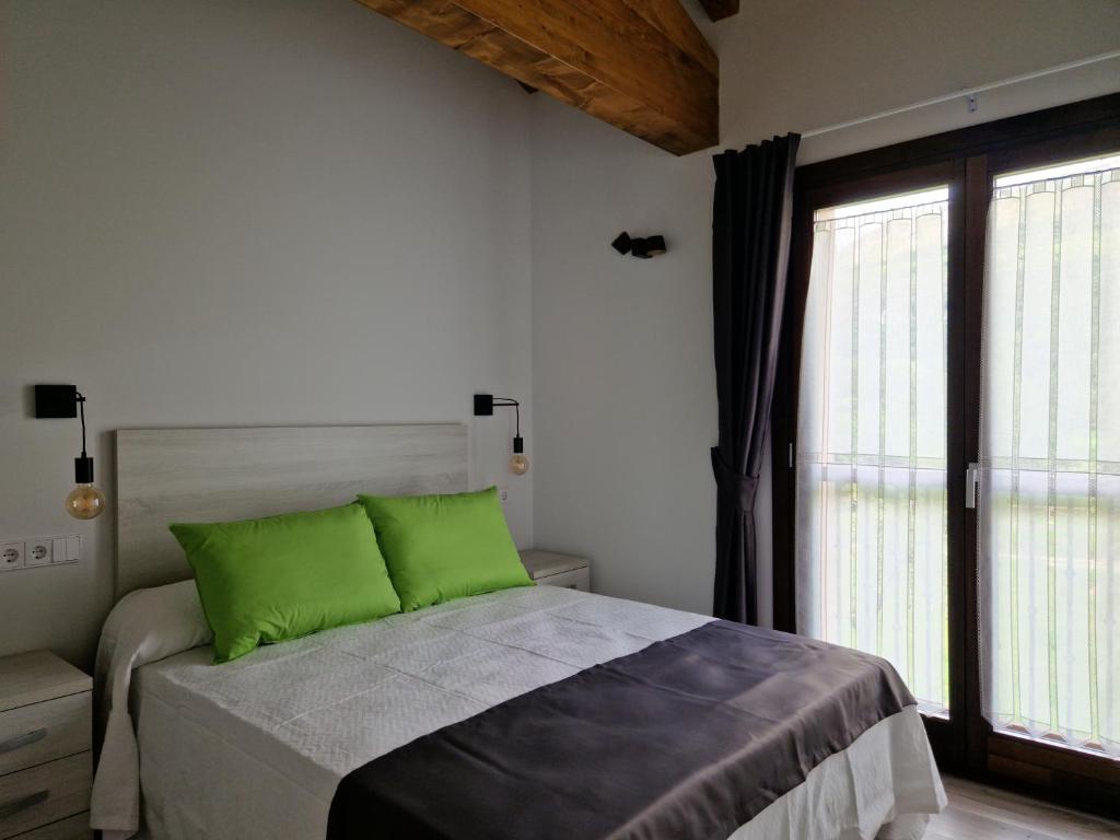 a bedroom with a bed with green pillows and a window at Apartamentos Villa de Panes - San Roque in Panes
