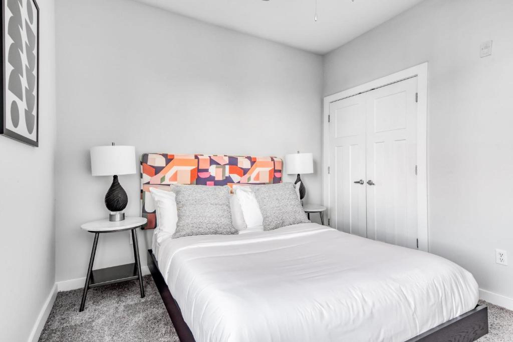 um quarto branco com uma cama e uma mesa lateral em CozySuites Music Row Charming 1BR free parking 49 em Nashville