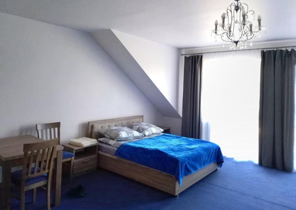 - une chambre avec un lit, une table et un lustre dans l'établissement Arkadia, à Przytyk