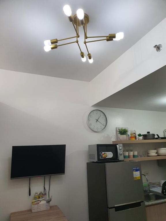 a kitchen with a tv and a clock on the wall at Stylish 1BR Condo @ SM Southmall in Manila