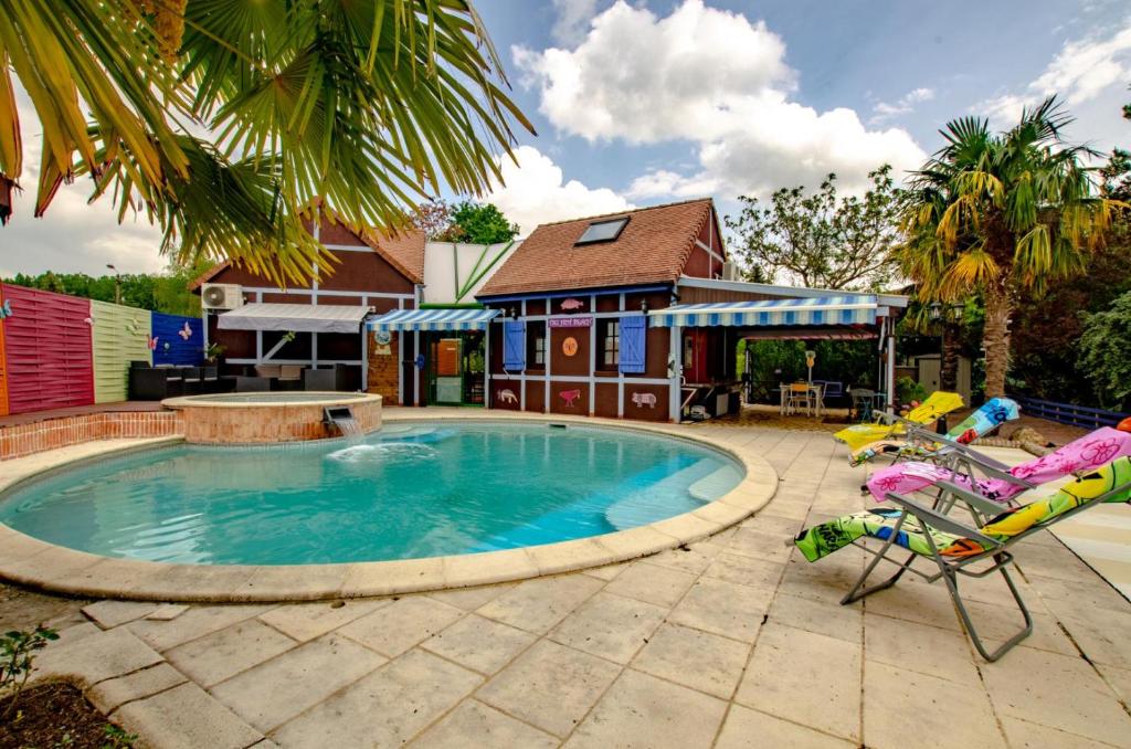 a swimming pool with two chairs and a house at Le tiki beach in Buchères