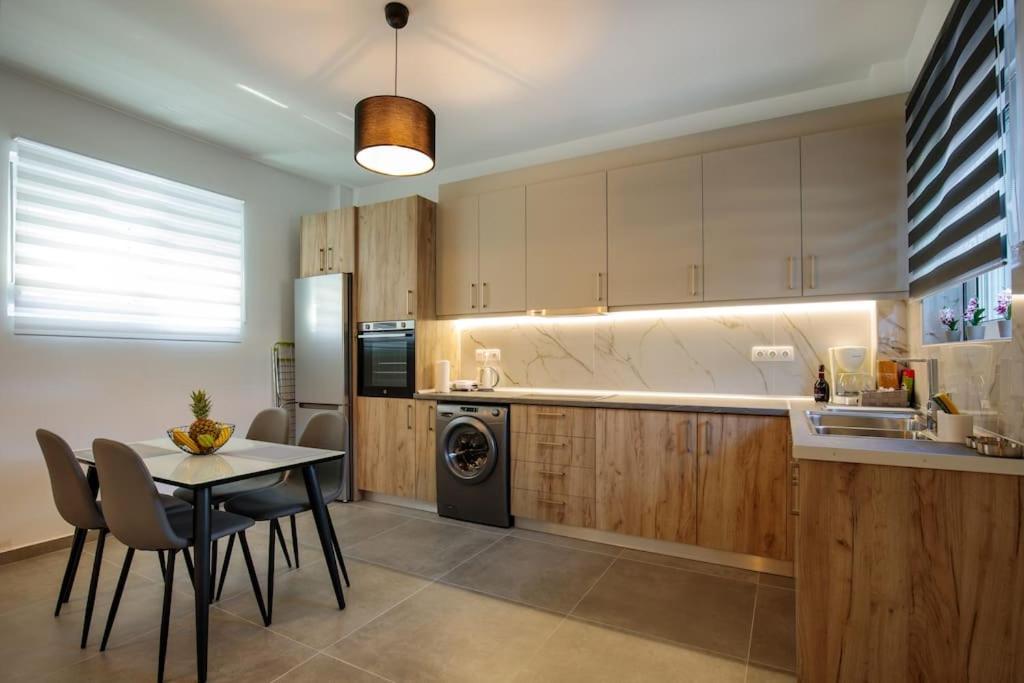 a kitchen with a table and chairs and a dishwasher at Michaela's Apartment in Koskinou