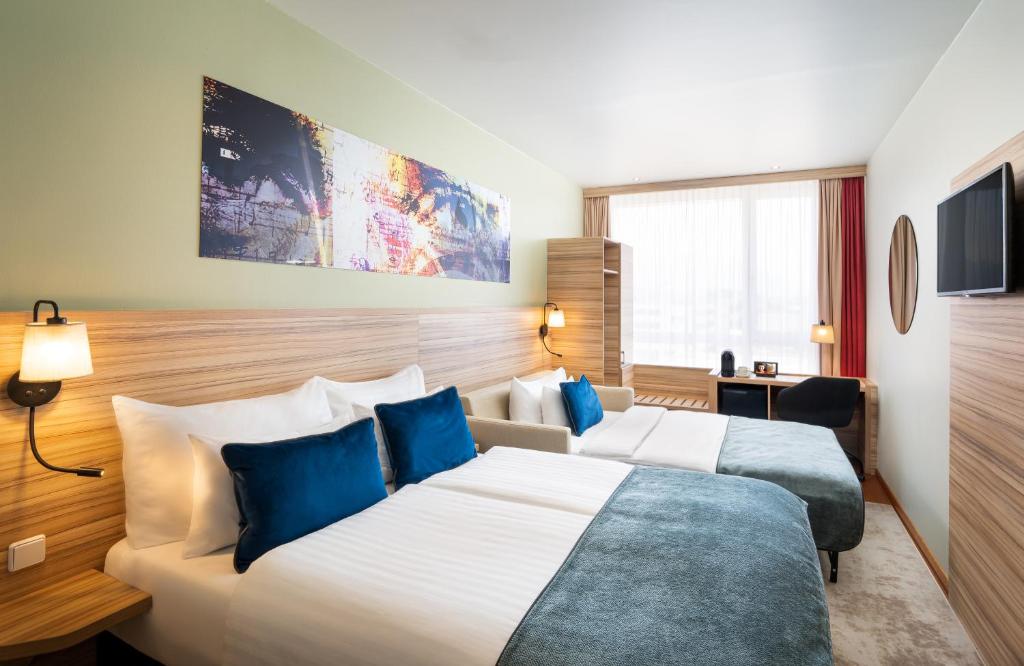 a hotel room with two beds and a tv at Leonardo Hotel Salzburg Airport in Salzburg
