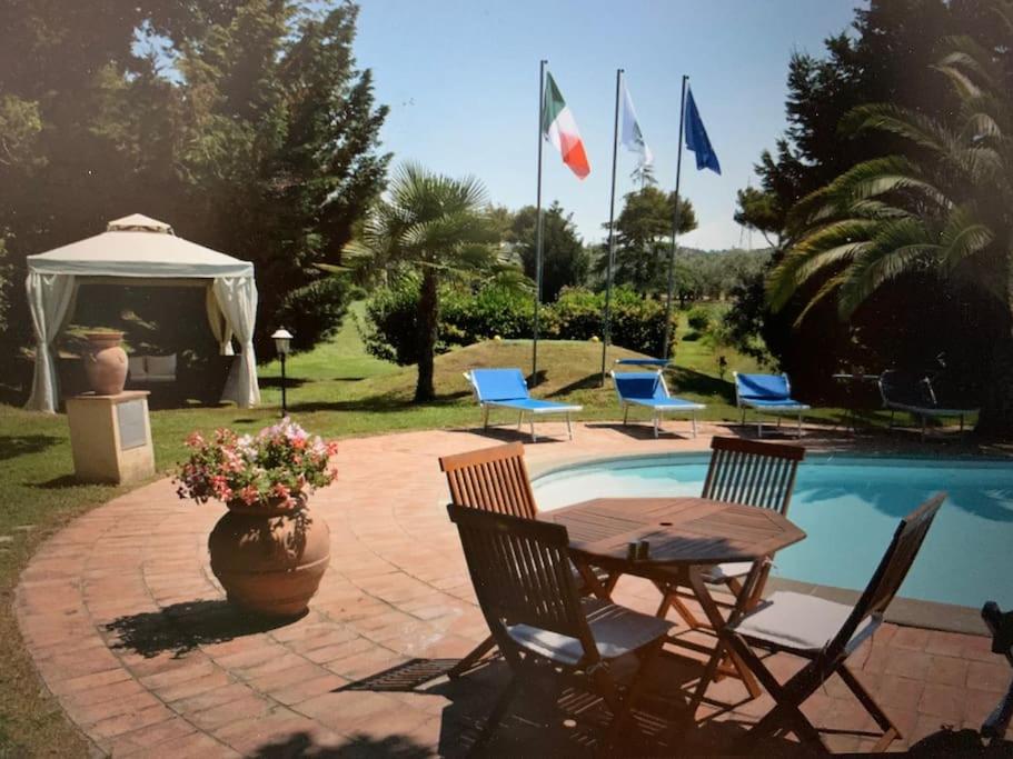 un patio con tavolo e sedie accanto alla piscina di Villa at Tuscany border, swimming pool, golfcourse a Tarquinia