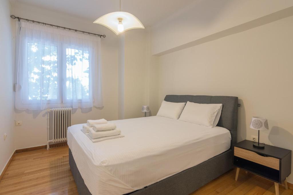 a bedroom with a bed with white sheets and a window at Aprtm Close To Arch Site & Museum Of Acropolis in Athens