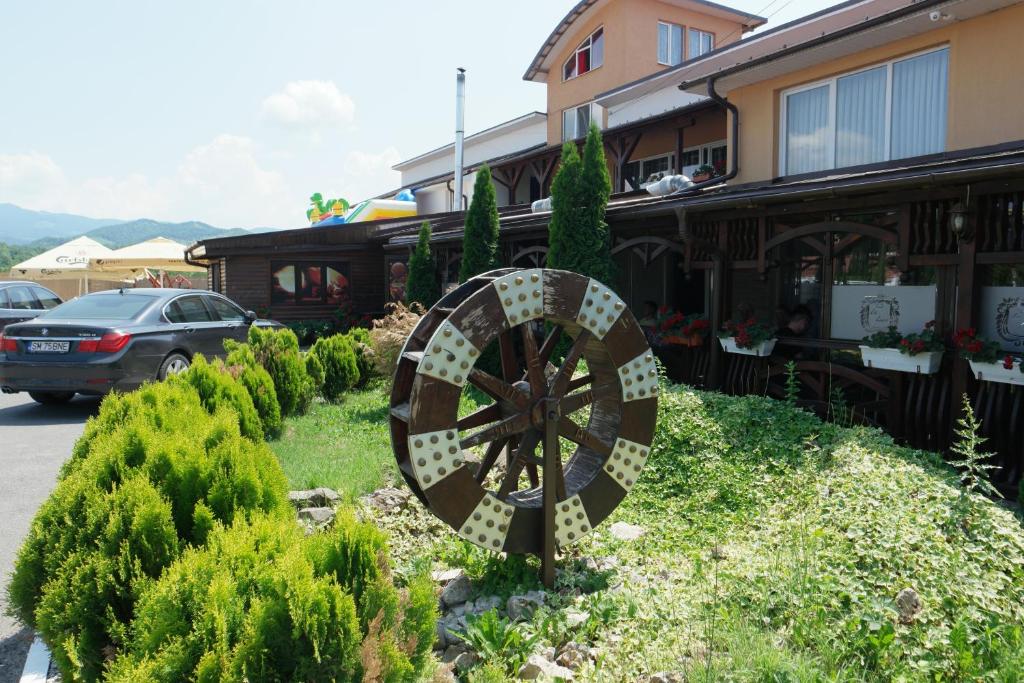 una rueda en un jardín frente a un edificio en Pensiunea La Luna en Negreşti-Oaş