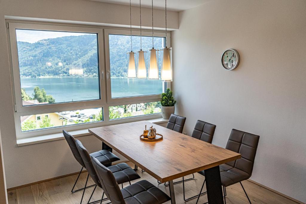 a dining room with a table and chairs and a large window at Top 9 Alpe Maritima - Lakeview Apartment mit Bergkulisse in Annenheim