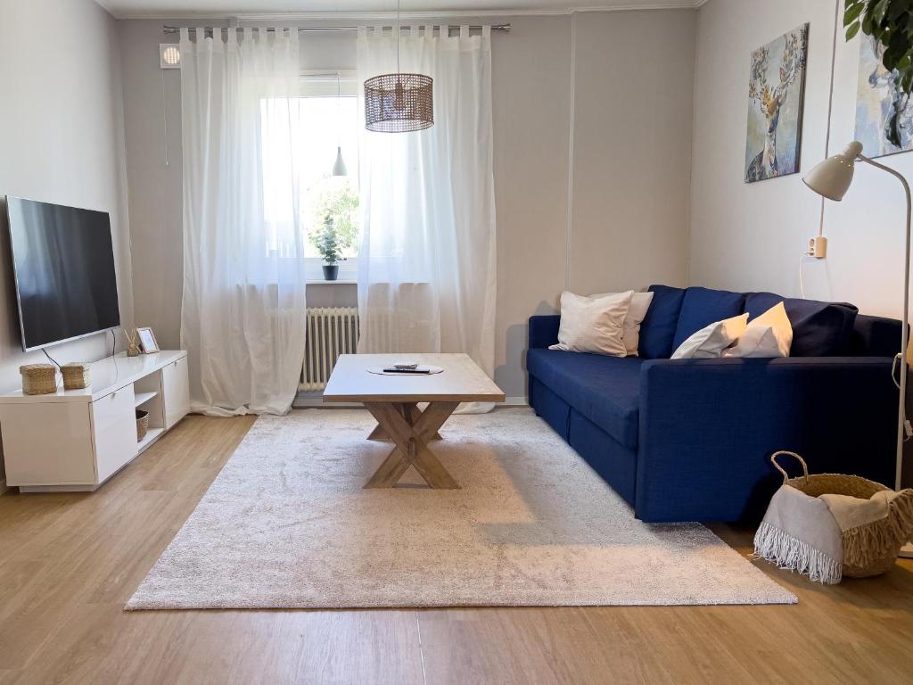 uma sala de estar com um sofá azul e uma mesa de centro em Långträsk Apartments Villa em Långträsk