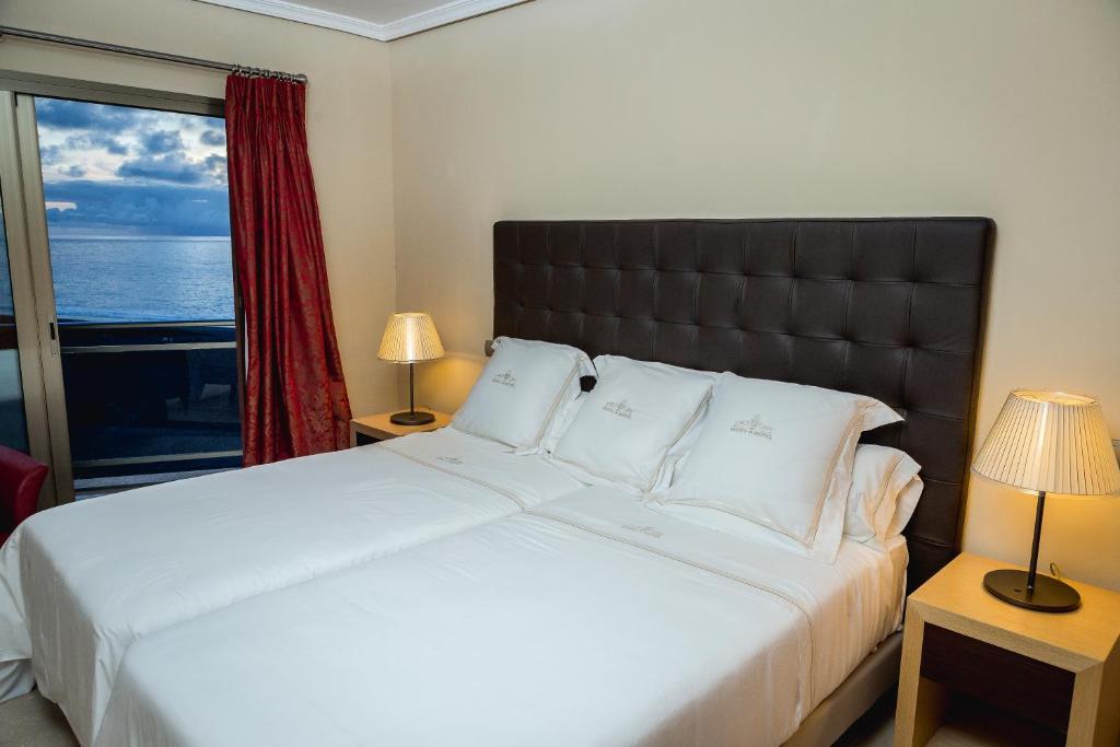 Un dormitorio con una gran cama blanca con ventana. en Balcón del Puerto, Ático-Solarium, en Tazacorte