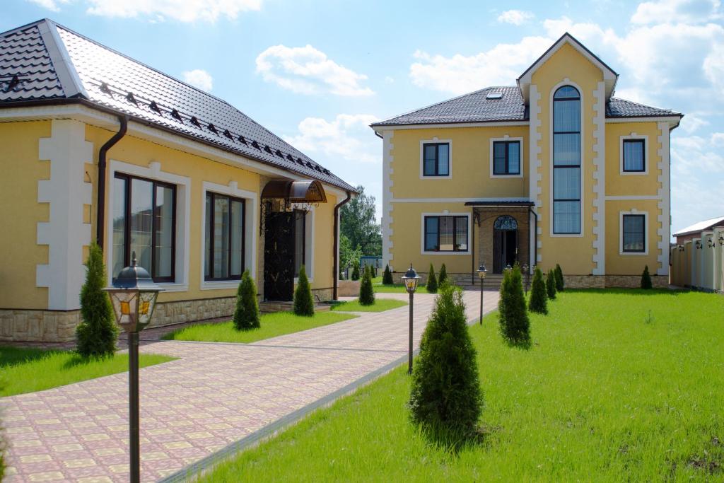 a large yellow house with a green lawn at Hotel Sharm in Khimki