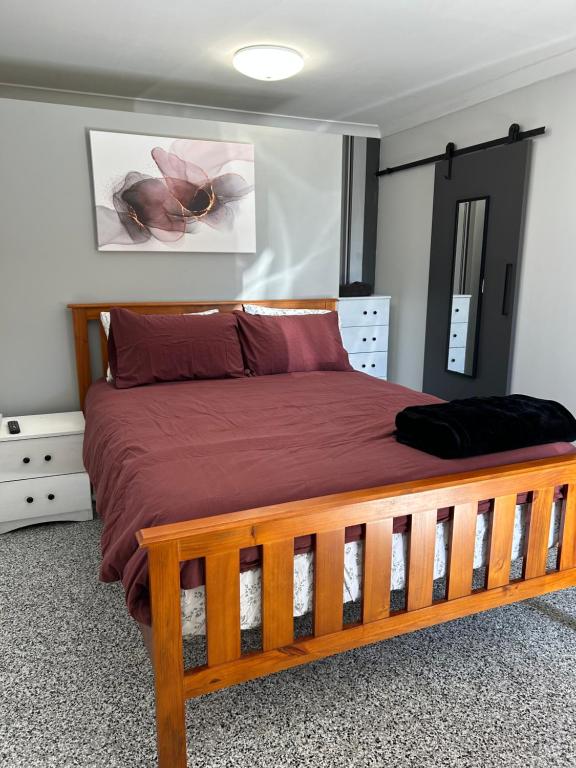 Clermont的住宿－Clermont Guest House - Pet friendly，一间卧室配有一张铺有红色床单的木床。