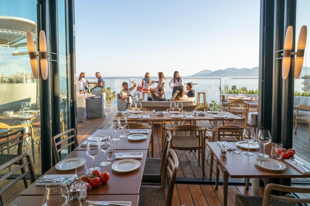 a restaurant with tables and chairs and a view of the ocean at Hôtel & Spa Belle Plage in Cannes