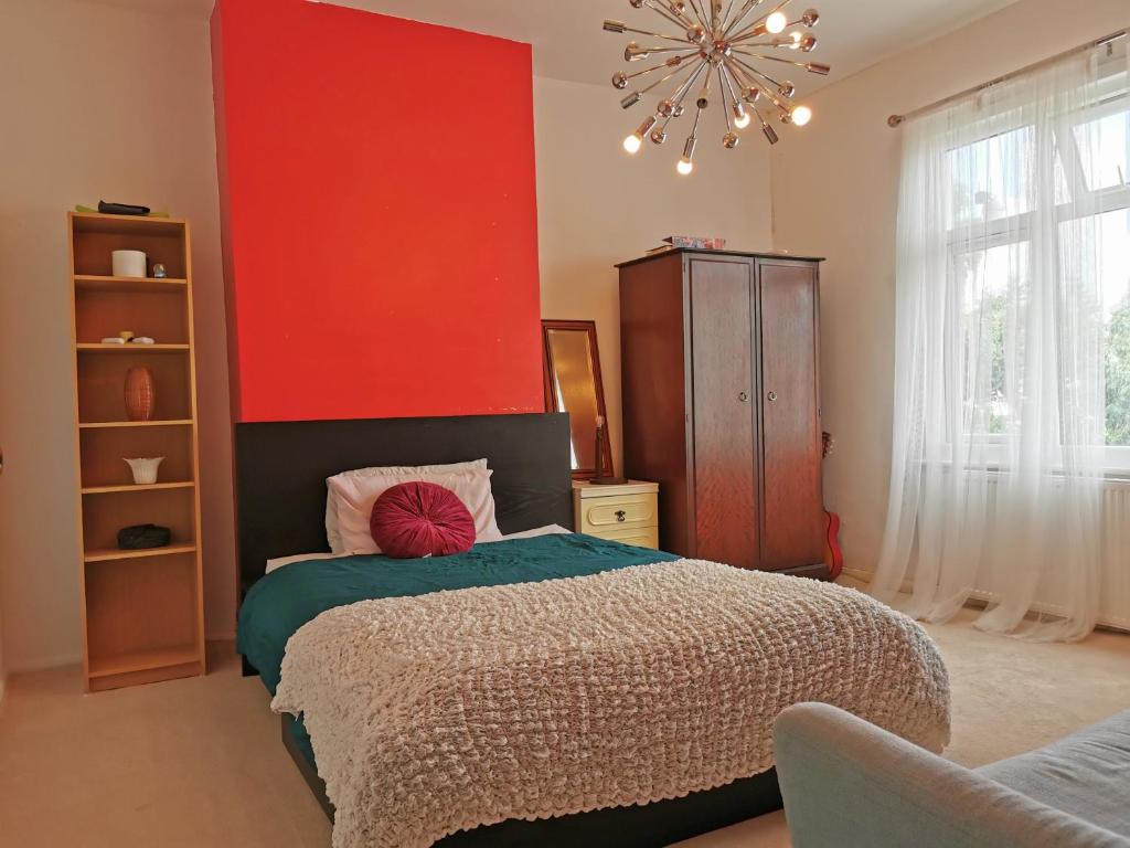 a bedroom with a bed with a red wall at Large Double Room with Private Toilet and Shower in Southend-on-Sea