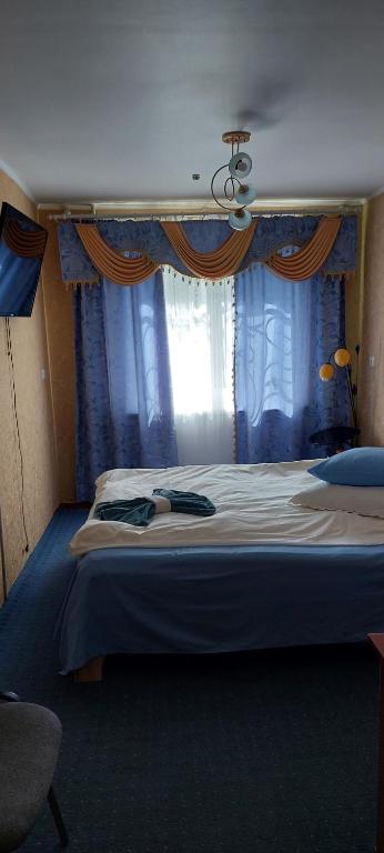 1 dormitorio con 1 cama grande y cortinas azules en Гостьові квартири Геолог en Stryi