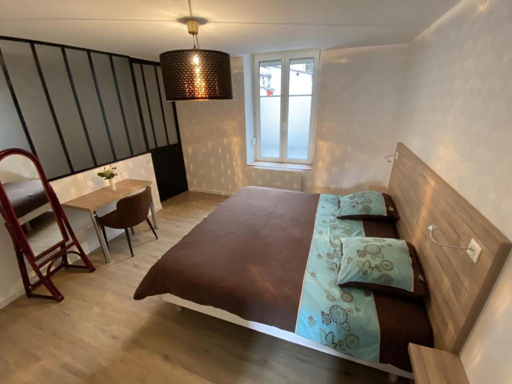 ein Schlafzimmer mit einem Bett und einem Tisch mit einem Stuhl in der Unterkunft Residence Gaby & Tom 4 Étoiles in Contrexéville