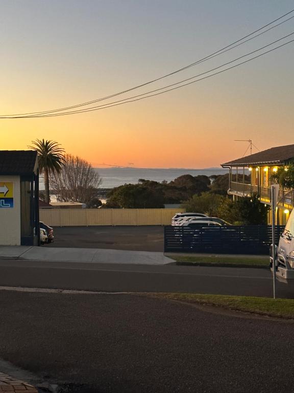 una vista de la puesta de sol de un aparcamiento con un edificio en Holiday Lodge Motor Inn, en Narooma