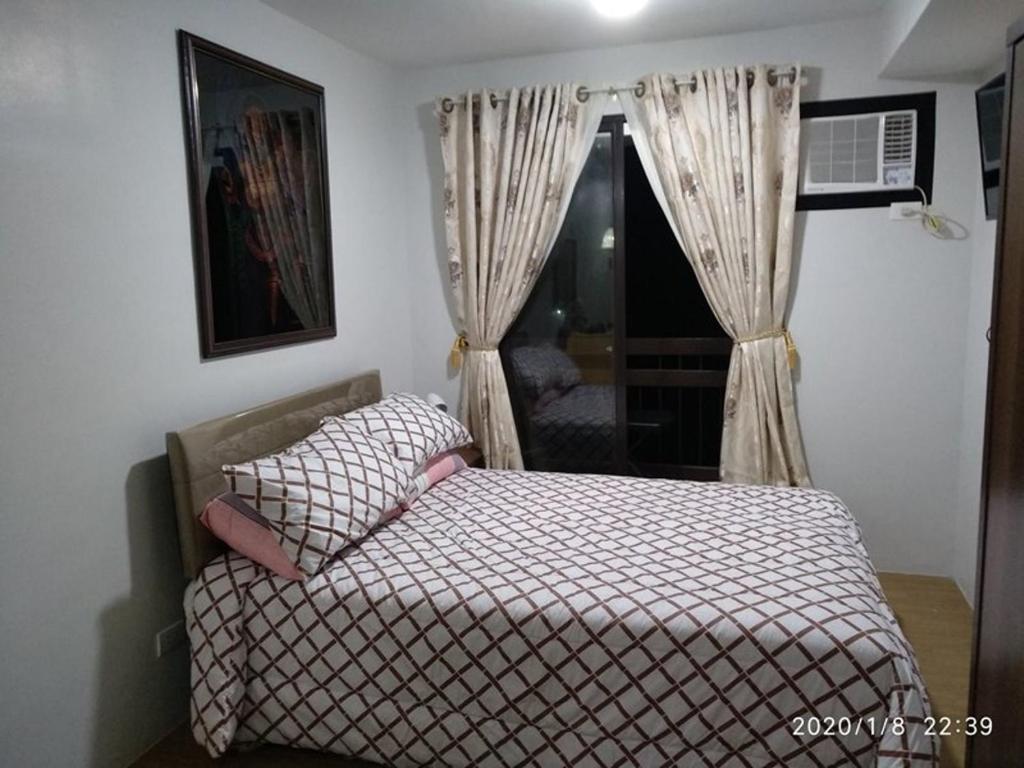 Schlafzimmer mit einem Bett und einem Fenster in der Unterkunft Pine Suites JR Studio, a Serene & Relaxing place in Tagaytay