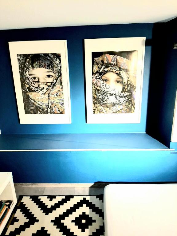 a blue wall with two framed pictures on it at Apartments House of Art in Nin