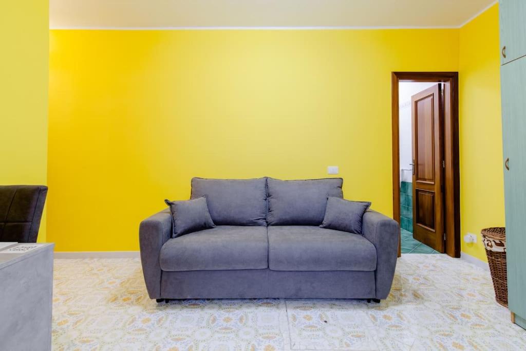 een bank in een kamer met een gele muur bij Pied-à-terre Casa Caterina in Ischia