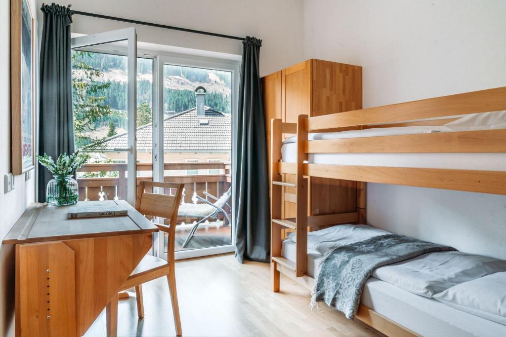 a bedroom with bunk beds and a desk and a balcony at Ferienhaus Florianiweg in Bad Gastein