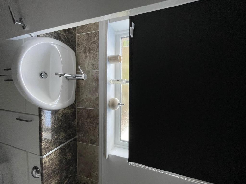 baño con lavabo y ventana en Luxury Spacious 2-Bed House in Brentwood Essex, en Brentwood