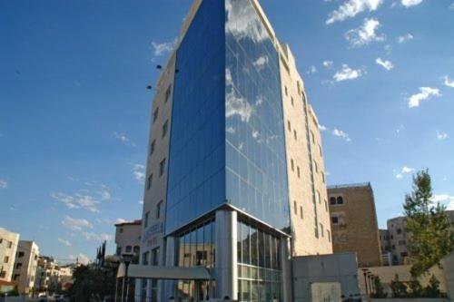 ein hohes Glasgebäude mit einem Spiegelbild des Himmels in der Unterkunft Galaxy Amman Hotel in Amman